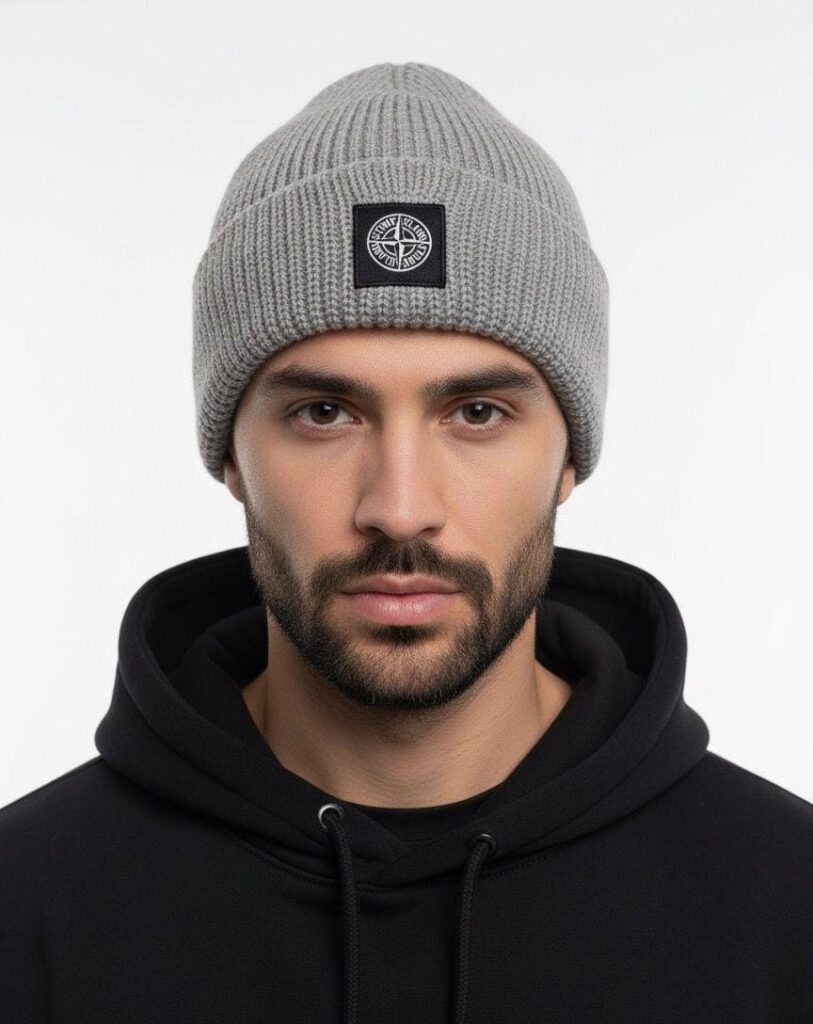 Açık gri fitilli örgü ve pusula amblemli bere takan erkek modeli